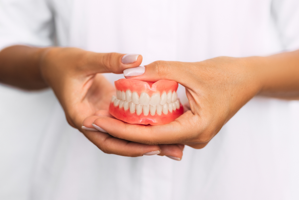 A close-up shot of a dentist holding dentures in her hands